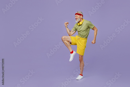 Full size body length fun elderly gray-haired bearded man 40s years old in headband khaki t-shirt tilt body to sides with hand stretch isolated on plain pastel light purple background studio portrait.