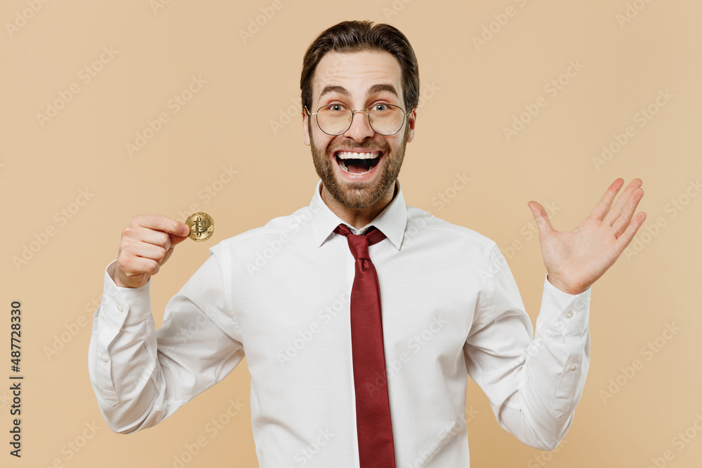 Young excited fun employee business man corporate lawyer 20s in classic white shirt red tie glasses work in office holding bitcoin coin currency spread hand isolated on plain beige background studio Young excited fun employee business man corporate lawyer 20s in classic white shirt red tie glasses work in office holding bitcoin coin currency spread hand isolated on plain beige background studio