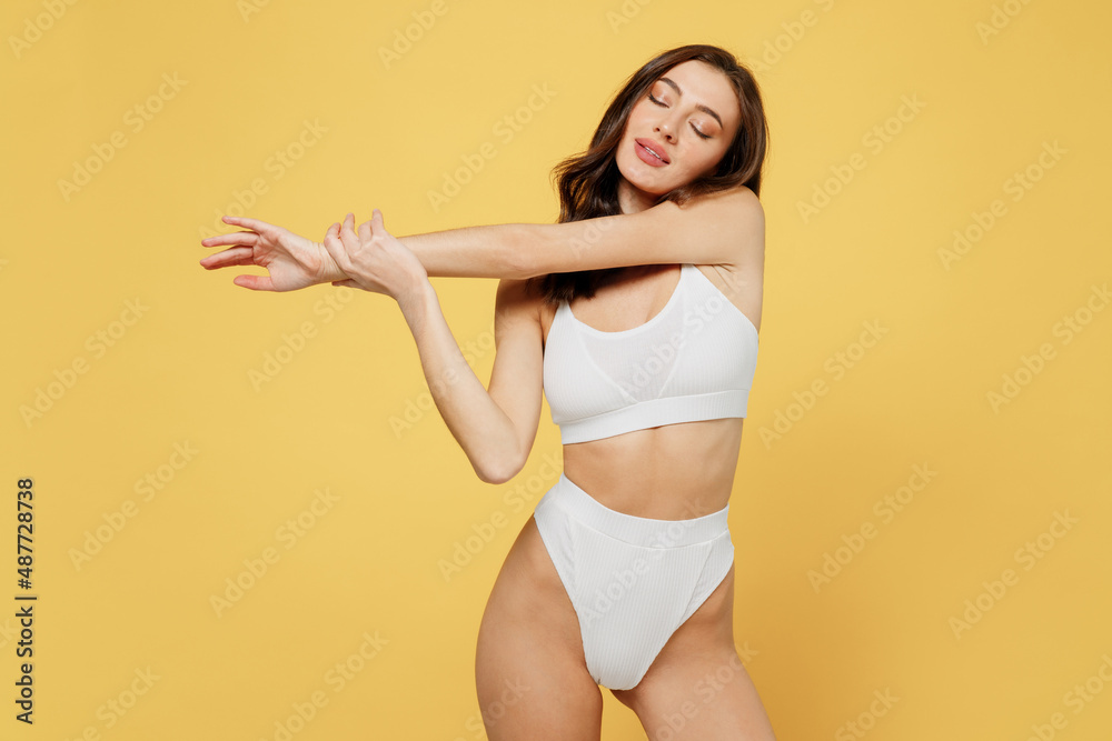 Tender calm slim lovely attractive young brunette woman 20s in white underwear with beautiful perfect fit body standing posing close eyes isolated on plain yellow colot background studio portrait Tender calm slim lovely attractive young brunette woman 20s in white underwear with beautiful perfect fit body standing posing close eyes isolated on plain yellow colot background studio portrait