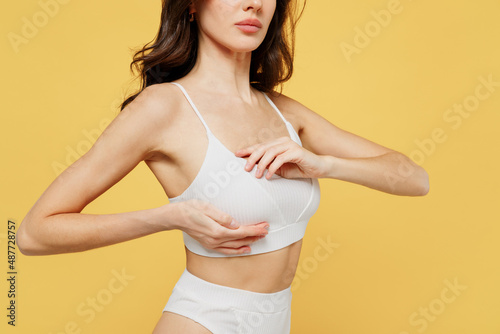 Canvas-taulu Cropped image side view of young woman 20s wearing white brassiere underwear put hand on chest breast cancer early diagnostic therapy treatment isolated on on plain yellow background studio portrait