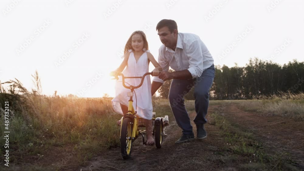 Little girl learning to ride bike on countryside path with family outdoors. Little girl learning to ride bike on countryside path with family outdoors.