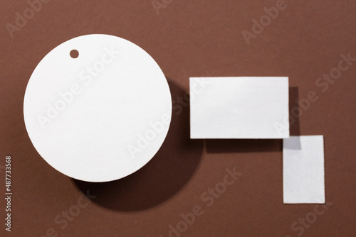 Three cardboard white colored brand blank tags of different shapes with circle on left and two rectangles on right put on brown background. Tag mock up. Copy space.
