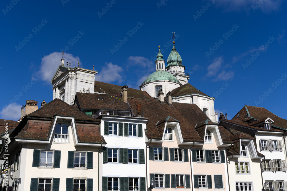 Fototapeta premium Historic colorful house facades at medieval alley with cathedral St. Ursen in the background at the old town of Solothurn on a sunny winter day. Photo taken February 7th, 2022, Solothurn, Switzerland.