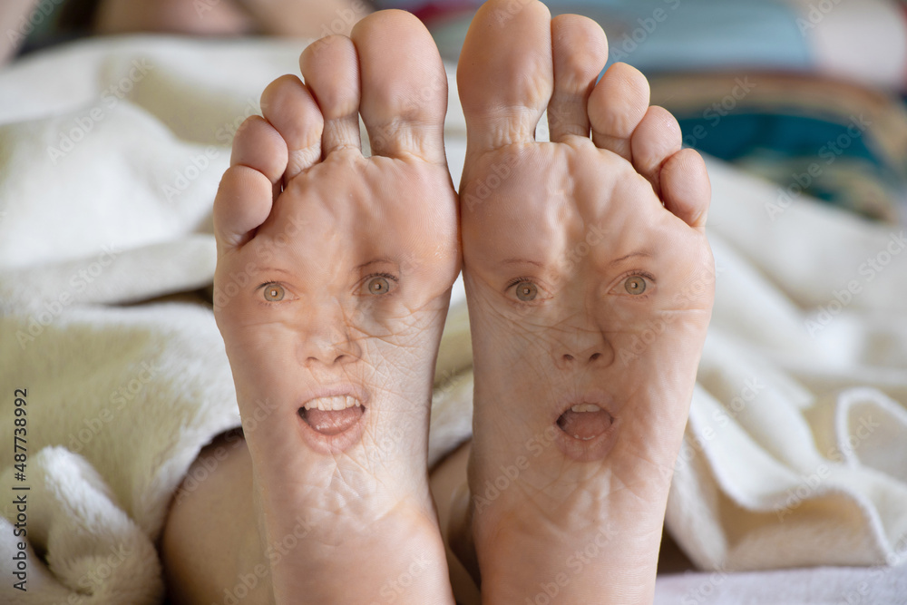 bare feet with girl's face on girl's leg on bed at home, face Stock Photo