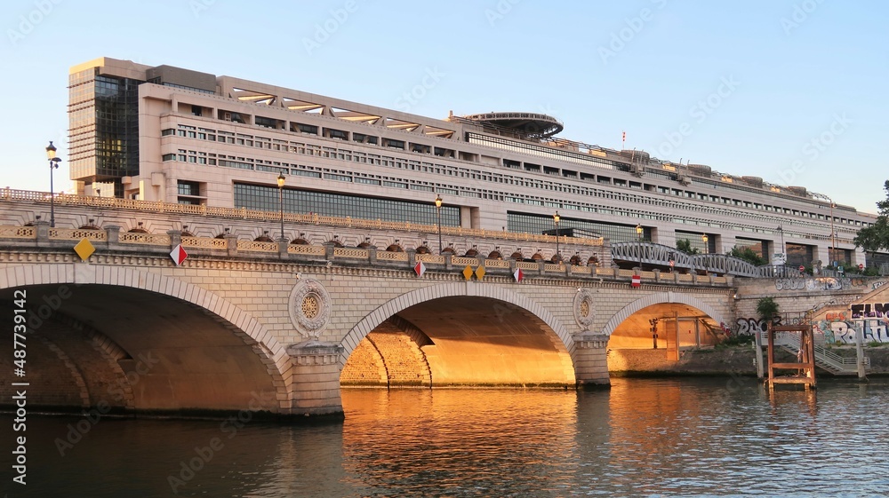 Naklejka premium Ville de Paris, pont de Bercy sur la Seine, au soleil couchant, avec le bâtiment du Ministère de l'Économie et des Finances français en arrière-plan (France)