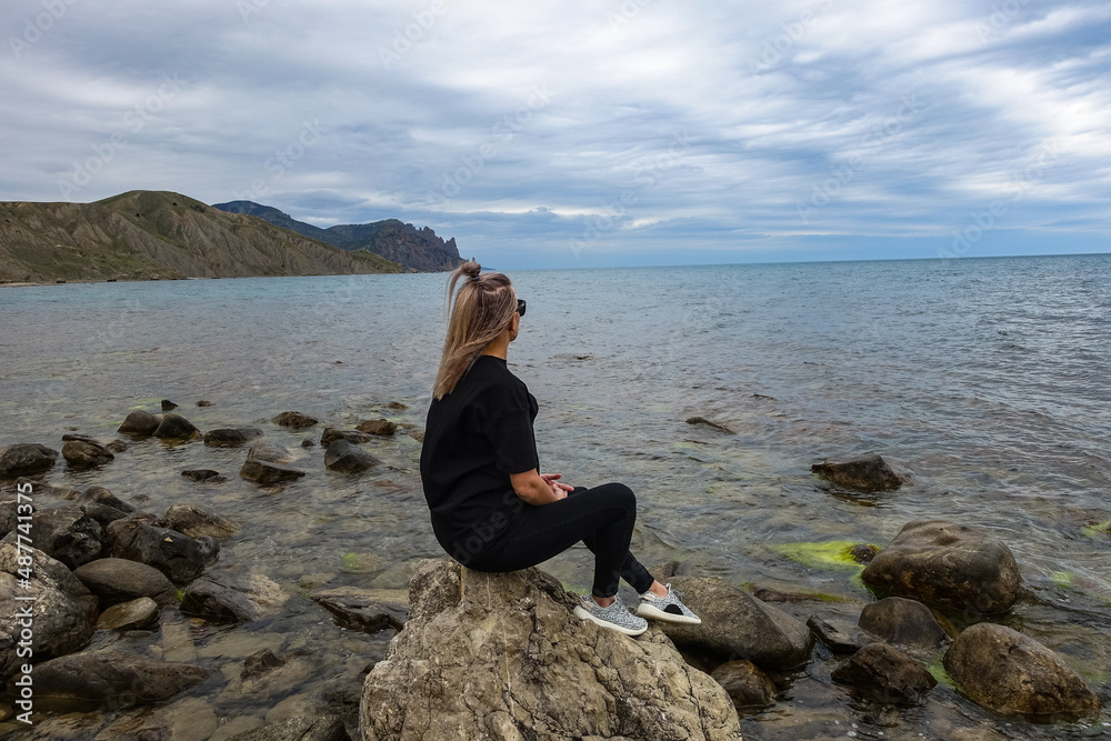 A girl on the shore of the Fox Bay - a bay of the Black Sea near the Kara-Dag mountain range. Crimea.