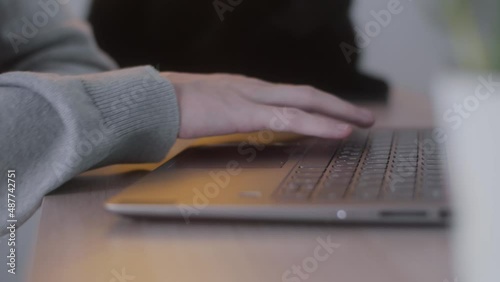 Women's hands are driving on a laptop touchpad, working with typing on a laptop keyboard, sitting at a home office desk, working online with PC software, application technology concept, close-up side 