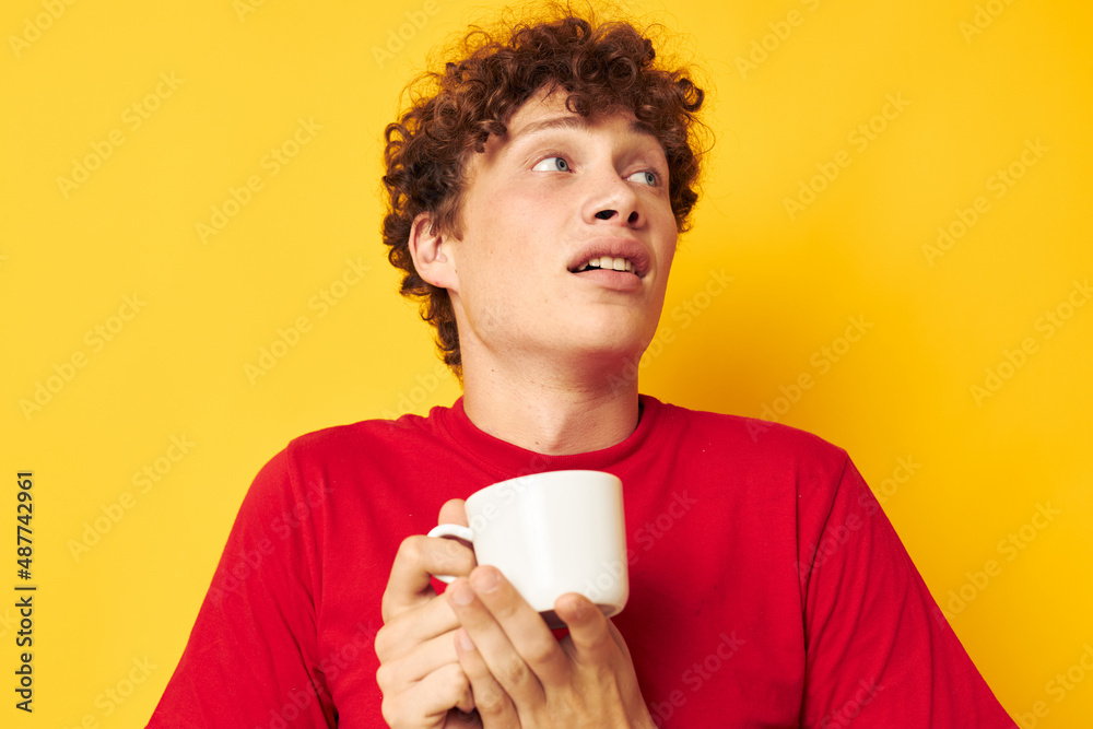 guy with red curly hair white mug in the hands of a drink yellow background unaltered guy with red curly hair white mug in the hands of a drink yellow background unaltered