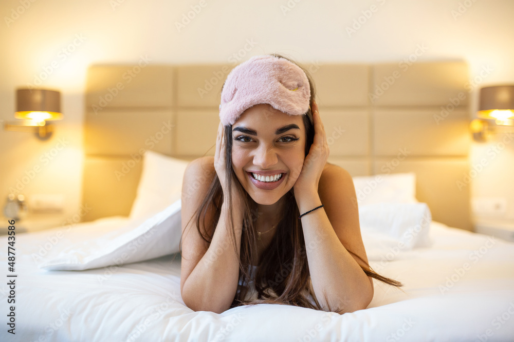Beautiful girl in bed with sleeping eye mask relaxing. beautiful excited woman in sleeping eye mask lying in bed Beautiful girl in bed with sleeping eye mask relaxing. beautiful excited woman in sleeping eye mask lying in bed
