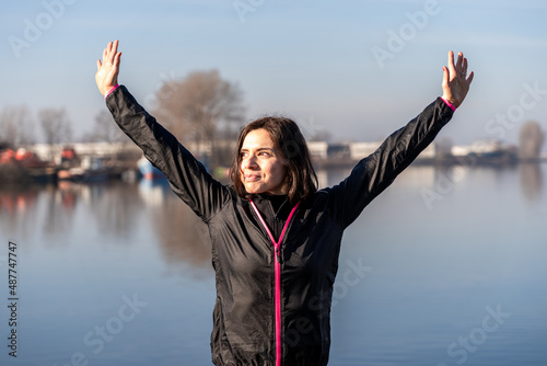 young female runner is putting her hands up on the quayside in the morning