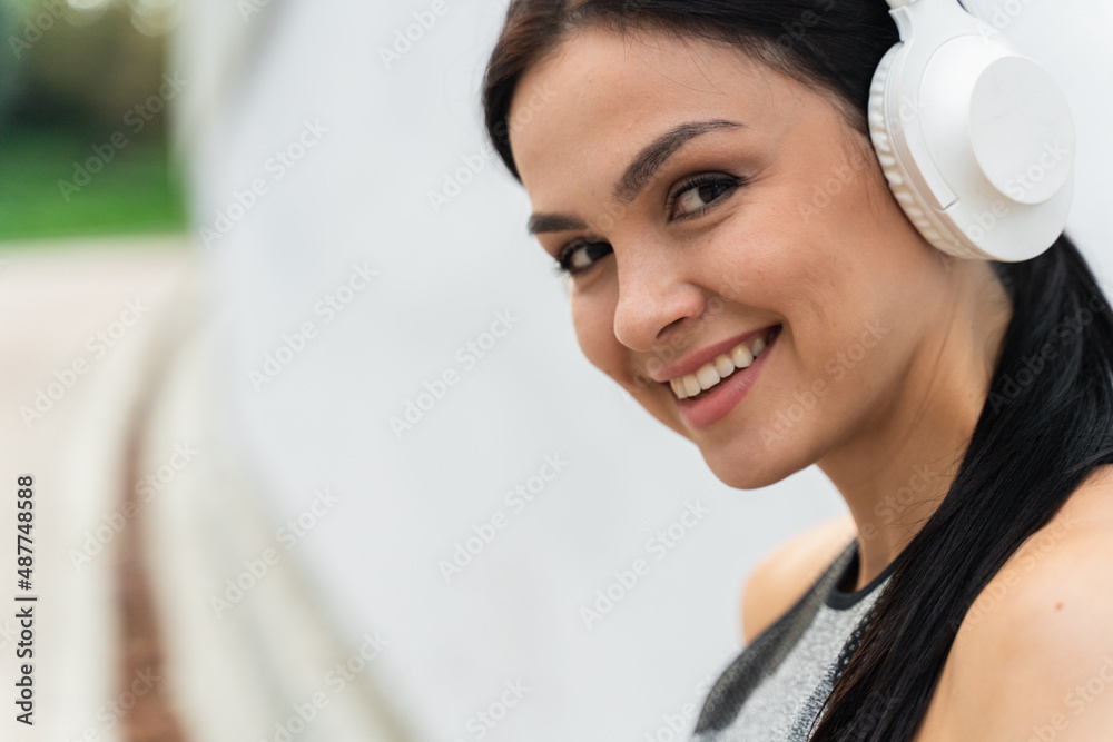 Joyful Caucasian female in wireless headphones looking ahead