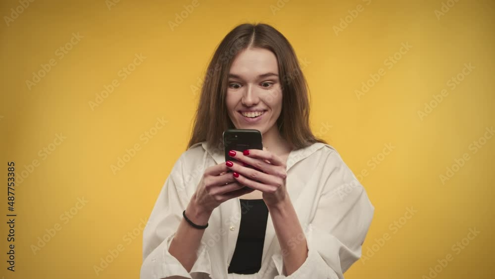 Young adult caucasian woman is celebrating an achievement on a bright yellow background Young adult caucasian woman is celebrating an achievement on a bright yellow background