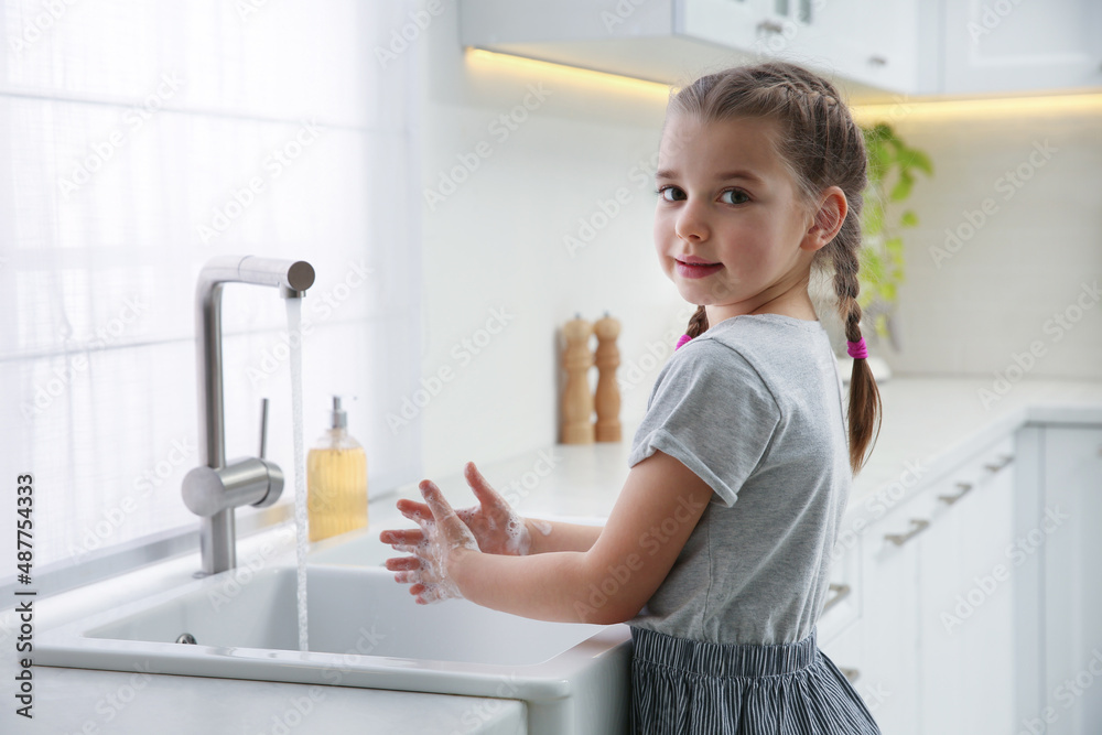 Cute little girl washing hands with liquid soap in kitchen Cute little girl washing hands with liquid soap in kitchen