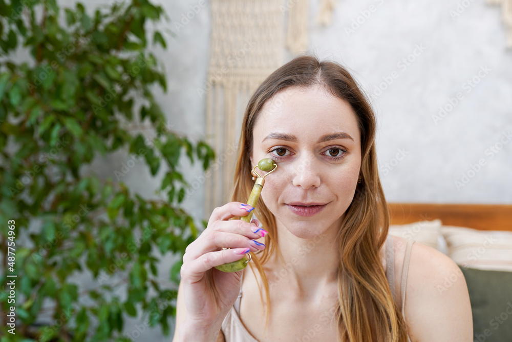 Young woman is doing Gua Sha facial massage in bathroom. Gua Sha jade stone at home treatment Young woman is doing Gua Sha facial massage in bathroom. Gua Sha jade stone at home treatment