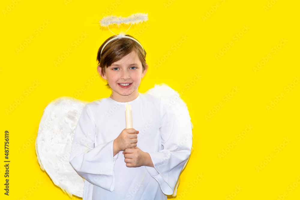 handsome boy dressed as an angel. child celebrates purim or halloween. celebration in church or baptism. yellow background handsome boy dressed as an angel. child celebrates purim or halloween. celebration in church or baptism. yellow background