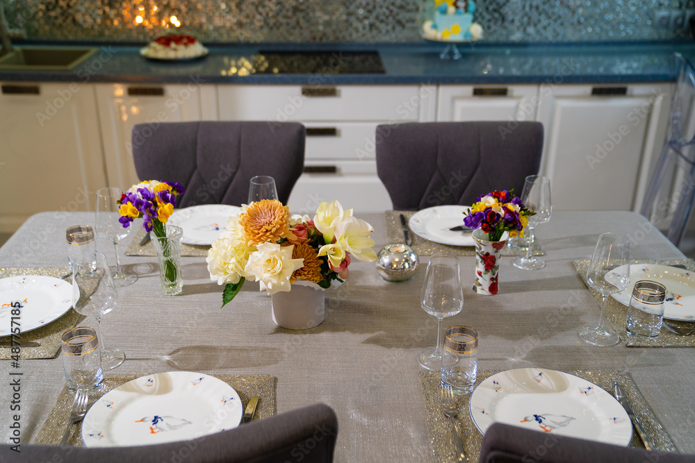 served dining table with utensils and flowers in the dining room. served dining table with utensils and flowers in the dining room.