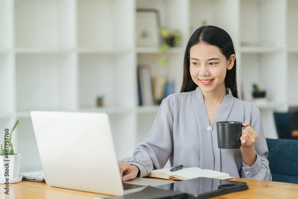 Portrait of young businesswoman sitting in office in front of computer and taking notes in notebook.Girl writer works on book,journalist writes article.Freelancer works remotely. Portrait of young businesswoman sitting in office in front of computer and taking notes in notebook.Girl writer works on book,journalist writes article.Freelancer works remotely.