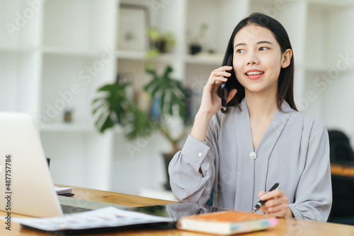 Wallpaper Mural Young business woman on the phone at office. Business woman texting on the phone and working on laptop. Pretty young business woman sitting on workplace. Smiling business woman. Torontodigital.ca