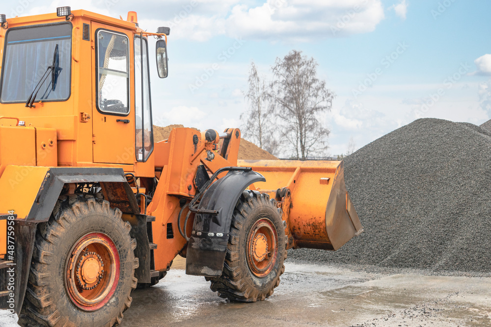 The front loader picks up gravel or crushed stone in the front bucket. Heavy construction machinery at the construction site. Transportation of materials at a concrete plant. The front loader picks up gravel or crushed stone in the front bucket. Heavy construction machinery at the construction site. Transportation of materials at a concrete plant.