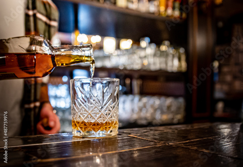 Barman pouring whiskey on glass in bar