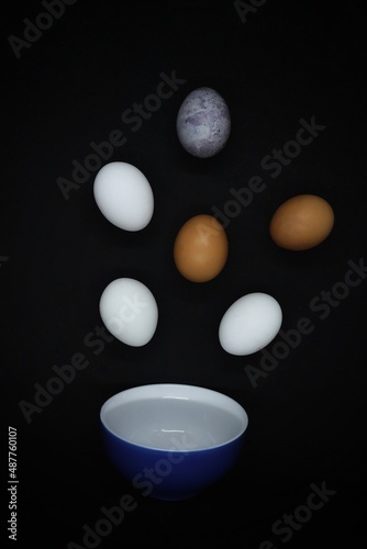 
Chicken eggs fly into a blue plate photo