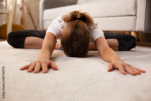 Young woman working out at home. Athletic woman in sportswear doing fitness stretching exercises..