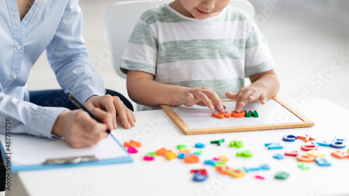 Cute little kid at speech therapist office. Close up of unrecognizable boy learning colorful English letters, free space