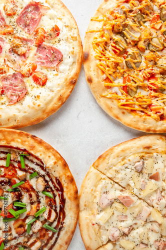 Pizzas on a gray background with pepperoni, basil, tomatoes and cheese