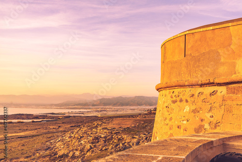 Old astle on coast and plastic greenhouse , Almeria Spain photo