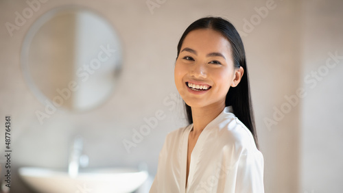 Obraz na plátně Cheerful pretty chinese lady smiling at camera, bathroom interior