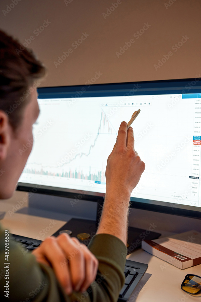 Trader watch and point on graph on computer Trader watch and point on graph on computer