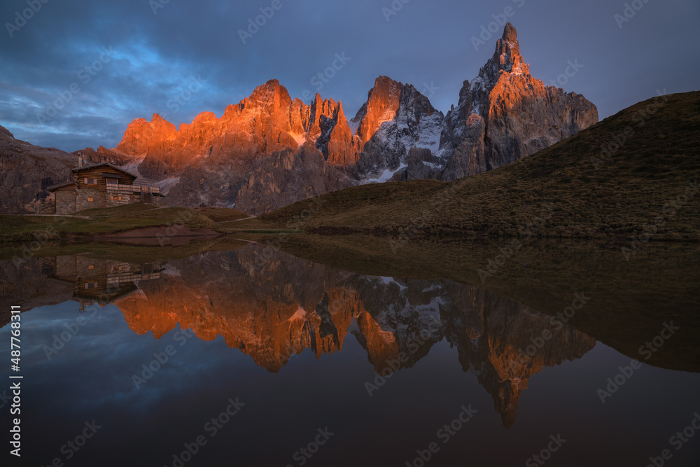 Golden sunlight during sunset on the beautiful ridge of Passo Rolle in Trentino, Dolomites.
The mountains here reflect beautifully into a small mountain lake.