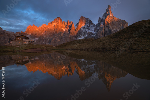 Golden sunlight during sunset on the beautiful ridge of Passo Rolle in Trentino, Dolomites. The mountains here reflect beautifully into a small mountain lake.