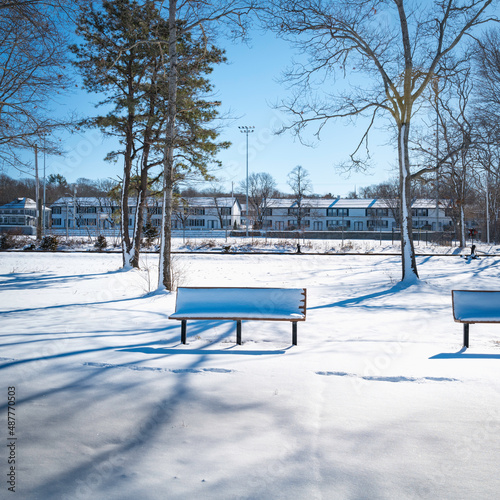 Empty benches in the park in the snow at Cape Cod Canal riverbank