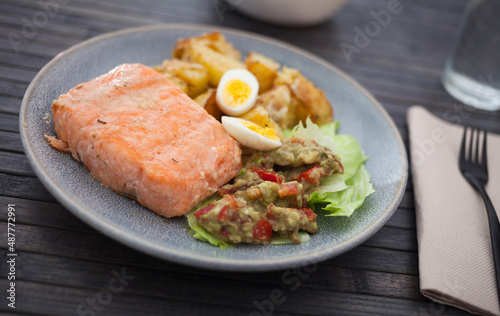 baked salmon fillet with fried potato wedges, homemade guacamole and quail eggs halves