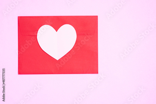 Red envelope with heart papercut on pink background