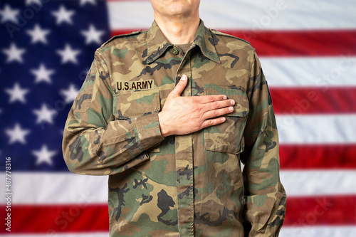 An American soldier man pledging allegiance in front of his country's flag photo