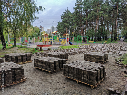 Pallets with old pavement tiles after dismantling in the city park next to the playground