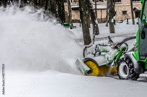 Snowplow on snow removal in the park puffs of snow from under a working machine photo