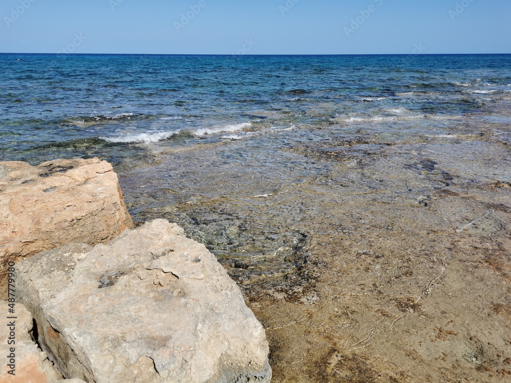 Protaras. Famagusta area. Cyprus. Large stones on the shores of the Mediterranean Sea, clear sea water and a cloudless sky.