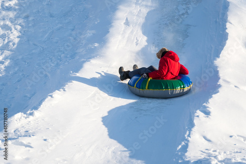A girl rides a tube from a slide in winter in a snowfall. Tubing, winter sports outdoor. Selective focus