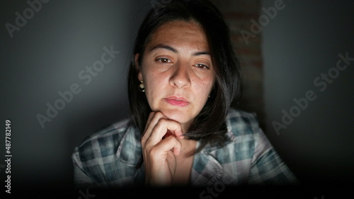 Woman in front of laptop on kitchen balcony late at night