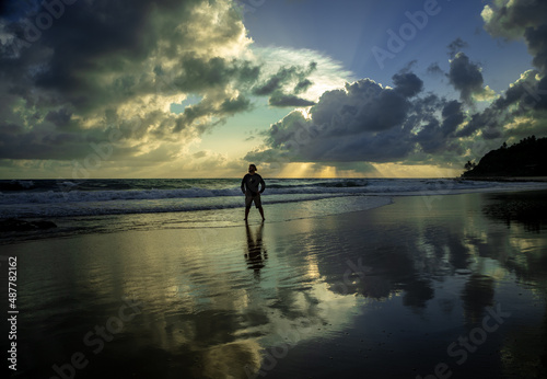 White man standing on a beach during sunrise.