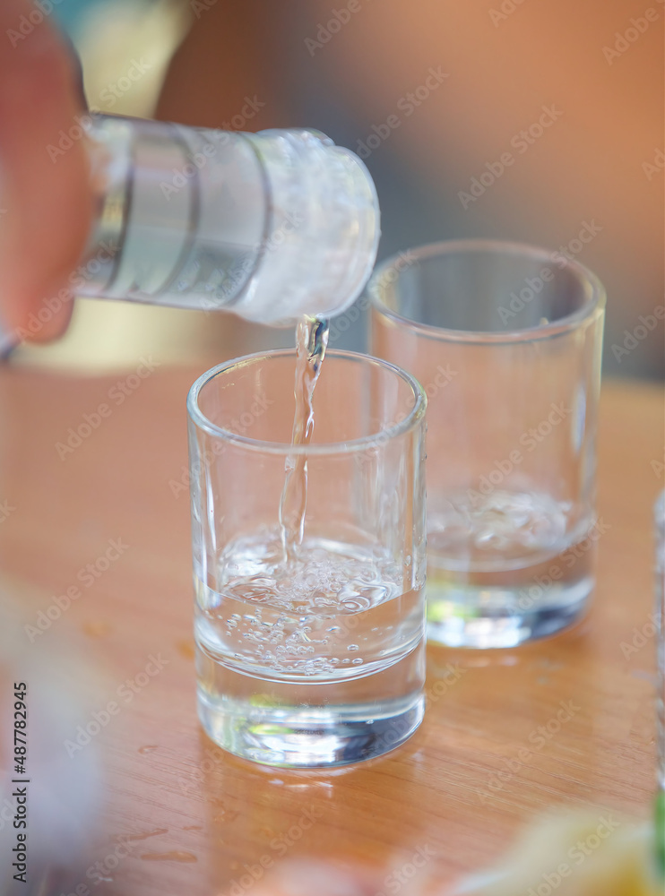Pour the alcoholic beverage vodka into a glass. Pour the alcoholic beverage vodka into a glass.