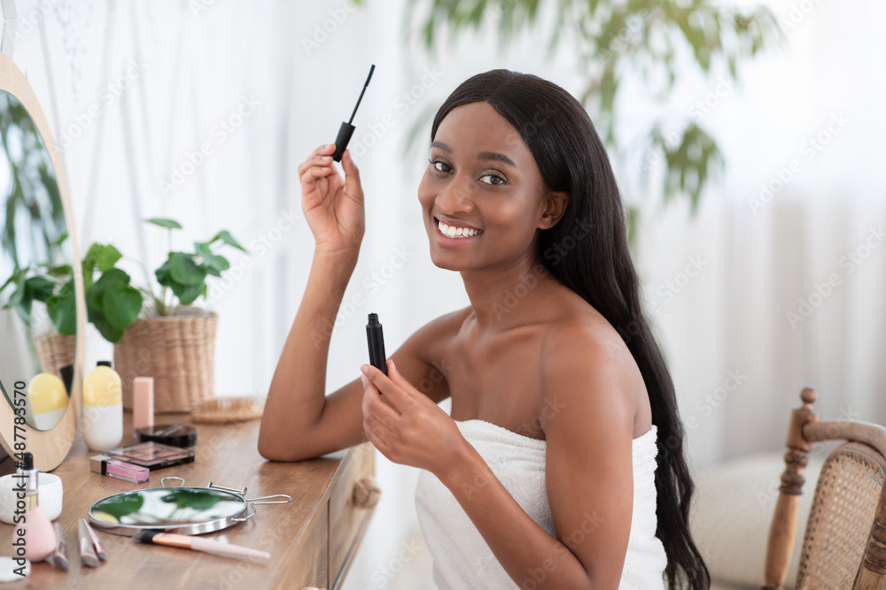 Morning routine makeup. Pretty millennial african american woman applying mascara on eyelashes Morning routine makeup. Pretty millennial african american woman applying mascara on eyelashes