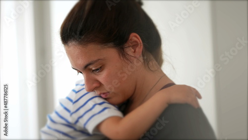 Mother multi-tasking at home holding child in arms