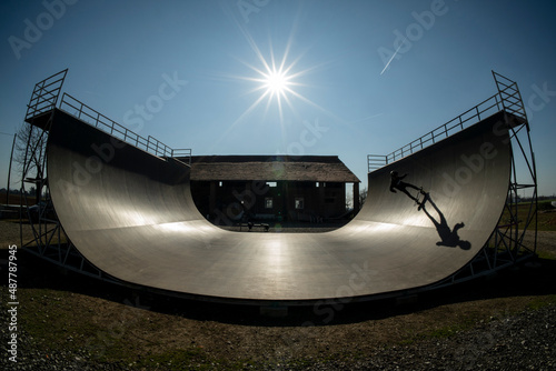 Young skateboarder in action, on a vert ramp with big shadow