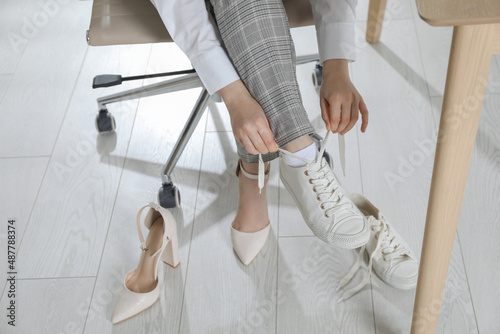 Woman changing shoes at workplace in office, closeup