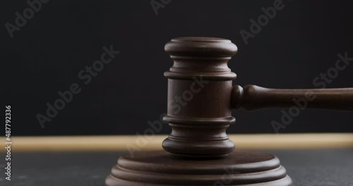 Judge pronouncing sentence striking wooden gavel. Judge hitting hammer against hardwood on black background.