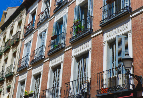 Classical facades of pastel colours and vintage balconies with shutters in Sol district downtown Madrid, Spain
